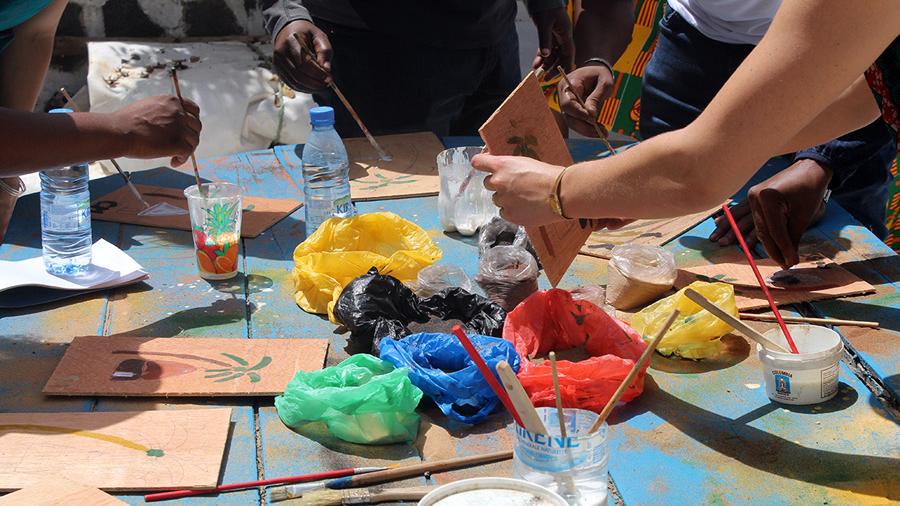 A diverse group of individuals sitting around a table, each holding paint and brushes.